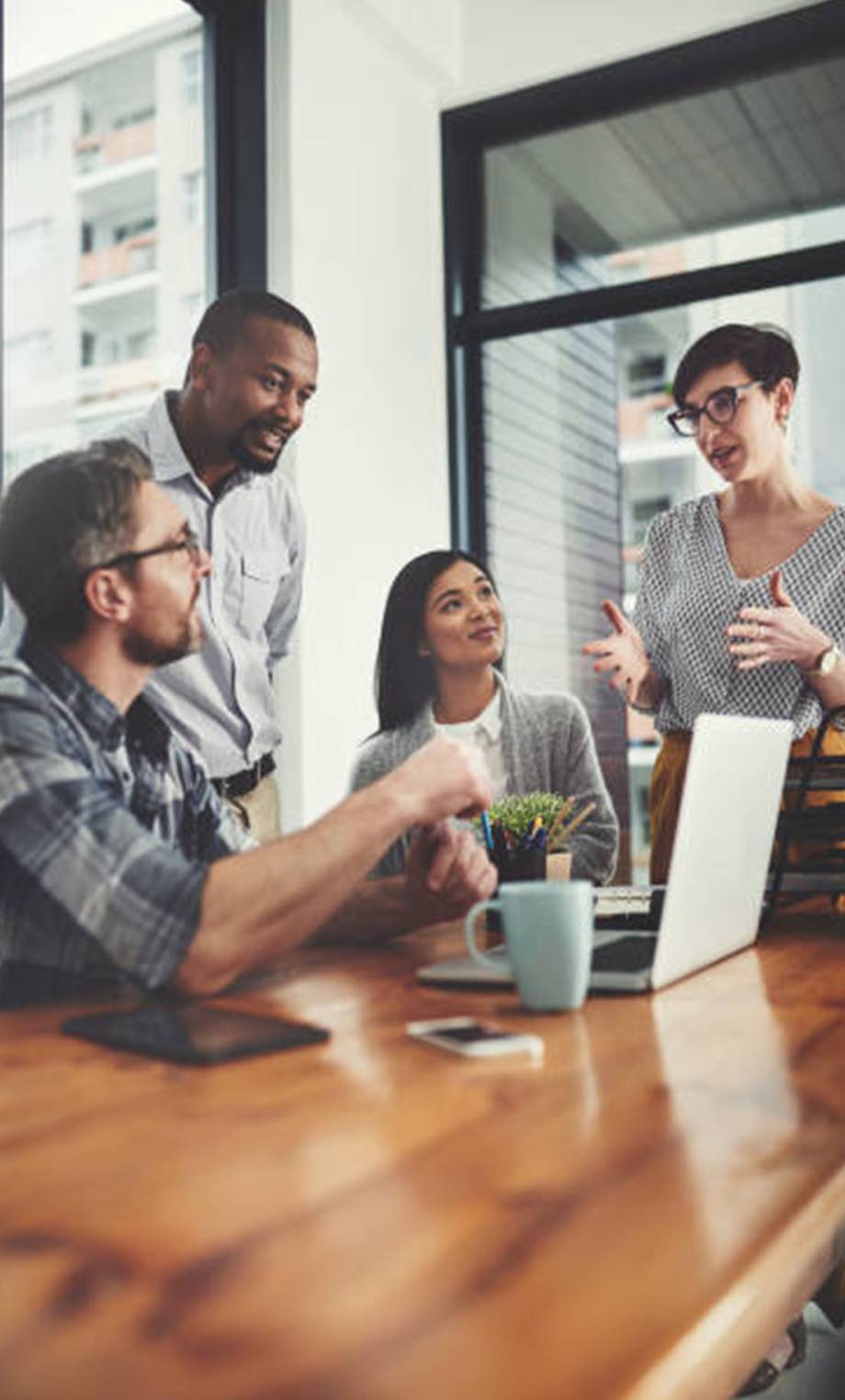Low angle shot of a group of businesspeople gathered around a laptop in their office